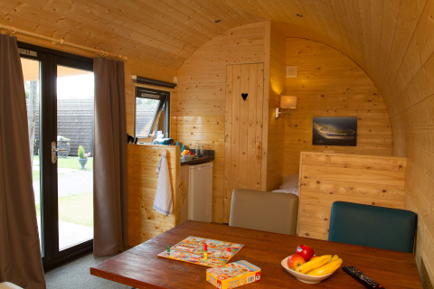 Vue intérieure d'une cabine en bois confortable au Nordsee Camp-Norddeich - Pods Oost-Friesland, avec table à manger.