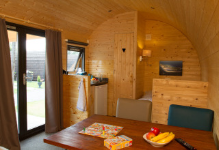 Interno di una pod in legno accogliente presso Nordsee Camp-Norddeich - Pods Oost-Friesland, con tavolo da pranzo.