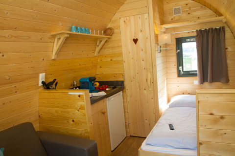 Interior of a cozy wooden pod with kitchenette, bed and window at Nordsee Camp-Norddeich, Oost-Friesland.