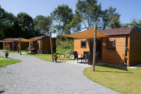 Træhytter på Nordsee Camp-Norddeich Pods Oost-Friesland omgivet af grønne træer og cykler i Danmark.
