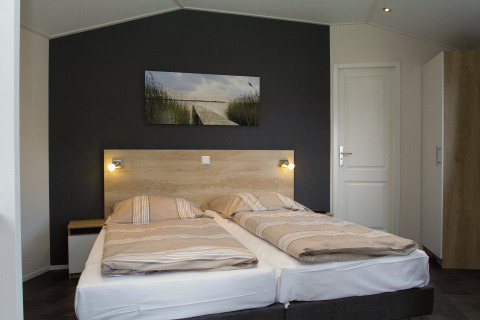 Alojamiento de glamping moderno en Nordsee Camp-Norddeich con dos camas, mesitas y arte en la pared.