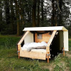 Glamping accommodation WERKHAUS destinature in a forest setting, featuring a cozy bed and wooden frame.