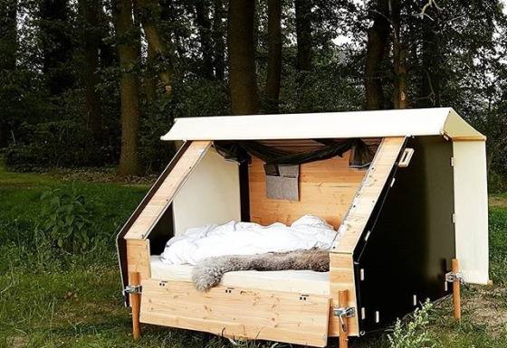 Hébergement glamping WERKHAUS destinature en forêt, lit confortable et cadre en bois chaleureux.