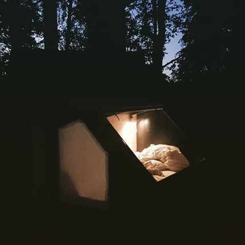 Glampingaccommodatie WERKHAUS destinature - Glamping Nedersaksen, gezellige verlichte tent in bos bij avond.
