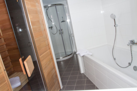 Bagno in un chalet glamping al Nordsee Camp-Norddeich con sauna, cabina doccia e vasca da bagno.