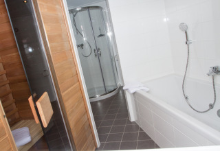 Salle de bains dans un chalet glamping au Nordsee Camp-Norddeich avec sauna, cabine de douche et baignoire.