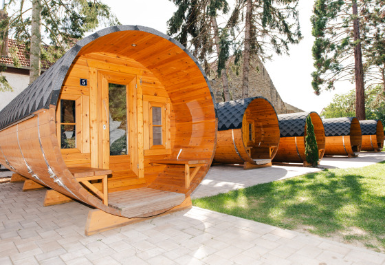 Rustieke wijnvaten glampingaccommodaties op de Glamping wijnroute Bockenheim, Pfalz, omgeven door bomen.