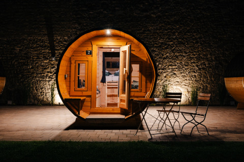 Round glamping accommodation shaped like a wine barrel on the Bockenheim wine route, Pfalz, lit at night.