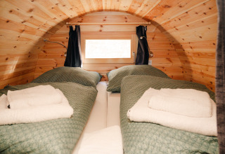 Hébergement glamping dans un tonneau à vin rustique avec deux lits simples et couettes vertes à Bockenheim, Pfalz.