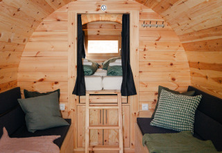 Intérieur d’un fût de vin rustique aménagé en glamping, bois, canapés et mezzanine à Bockenheim.