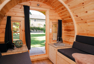 Interno di una botte in legno per glamping, con tende scure e vista sul giardino a Bockenheim, Pfalz.