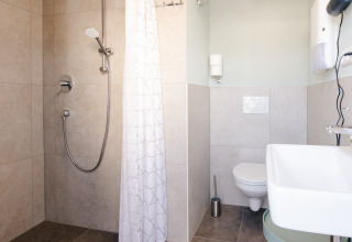 Bagno moderno con doccia, tenda, lavabo e WC in sistemazione glamping in botte di vino a Bockenheim, Pfalz.