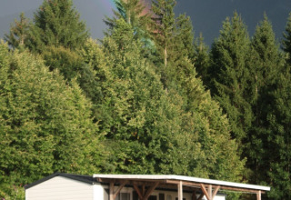 Glamping accommodatie of camping bij Camping Rosental Roz in Oostenrijk met regenboog en bos op de achtergrond.