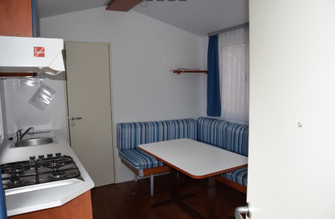 Intérieur d’un hébergement glamping au Camping Rosental Roz avec coin cuisine, table et banquette.