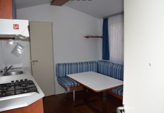 Interior of a glamping accommodation at Camping Rosental Roz with kitchenette, dining table and seating.