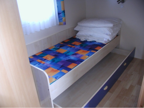 Habitación individual con cama de colores, cama supletoria extraíble y ropa de cama en Camping Rosental Roz.