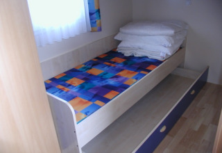 Eénpersoonskamer met kleurrijk bed, extra uitschuifbed en beddengoed bij Camping Rosental Roz.