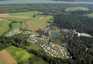 Luchtzicht op Camping Rosental Roz - Stacaravans Oostenrijk, tussen groene velden, bos en een centrale vijver.