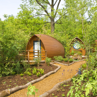Ronde houten hutten tussen groen bij Glamping Resorts Biosphere Bliesgau met tuinpaden en veel natuur.