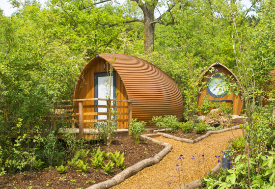 Runde træhytter i naturskønne omgivelser på Glamping Resorts Biosphere Bliesgau med grønne planter og stier.