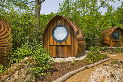 Sistemazioni glamping al Biosphere Bliesgau: cabine rotonde in legno immerse nella natura verde e rigogliosa.