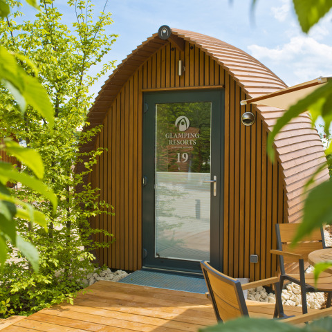 Glampingindkvartering ved Glamping Resorts Biosphere Bliesgau med træhytte og udendørs siddeplads.
