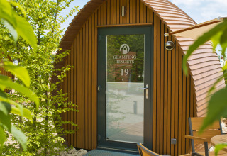 Alojamiento glamping en Glamping Resorts Biosphere Bliesgau con cabaña de madera y zona para sentarse fuera.