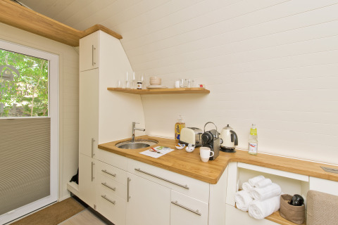Kitchenette moderne au Glamping Resorts Biosphere Bliesgau avec plan en bois, grille-pain et bouilloire.