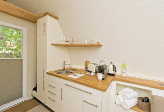 Moderna cocina pequeña en Glamping Resorts Biosphere Bliesgau con encimera de madera, tetera y tostadora.