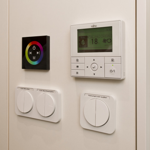 Wall-mounted control panels for lighting and heating at Glamping Resorts Biosphere Bliesgau, stylish setup.