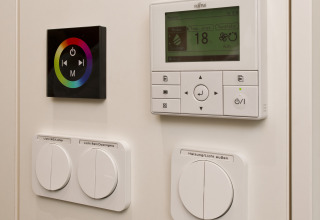 Wall-mounted control panels for lighting and heating at Glamping Resorts Biosphere Bliesgau, stylish setup.