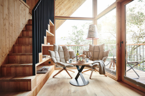 Moderne Glamping-Unterkunft mit Holzinterieur, gemütlicher Sitzecke und großer Fensterfront in Tirol.