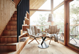 Alloggio glamping moderno con area lounge accogliente e grandi finestre nello Chalet Boomhut Tirol HochLeger.