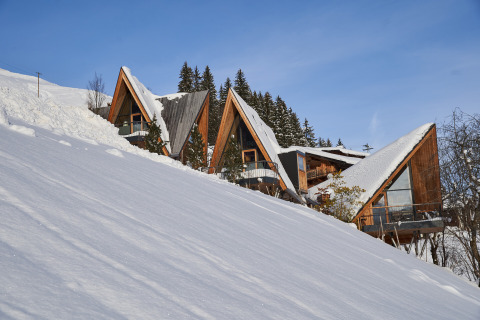 Glamping accommodation HochLeger Chalet Refugium - Boomhut Tirol set amid snowy Alpine slopes in Austria.