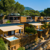 Luxury glamping lodges at Camping Bonporteau in South France, surrounded by trees and mountains in sunlight.