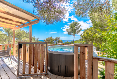Holzterrasse mit Whirlpool und traumhaftem Ausblick auf Wald und Meer bei Camping Bonporteau Glamping Südfrankreich.