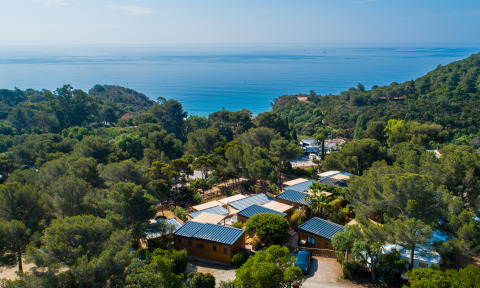 Vista aérea de Camping Bonporteau - Glamping Sur de Francia, rodeado de bosque y con el mar al fondo.