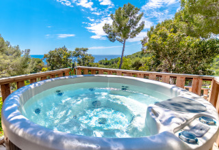 Jacuzzi al aire libre con vistas al bosque y mar en Camping Bonporteau - Glamping Sur de Francia, día soleado.