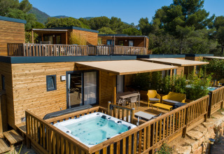 Hébergement glamping moderne au Camping Bonporteau, Sud de la France, avec jacuzzi privé et terrasse boisée.