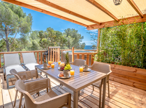 Glamping-Terrasse bei Camping Bonporteau in Südfrankreich mit Meerblick, Obst, Saft und Liegestühlen.