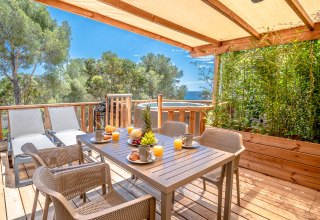 Glamping terras bij Camping Bonporteau, Zuid-Frankrijk, met uitzicht op zee, fruitontbijt en ligstoelen.