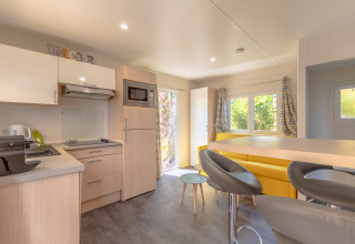 Modern glamping accommodation at Camping Bonporteau with kitchen, yellow sofa, and natural light in South France.