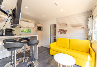 Lichte glamping woonkamer bij Camping Bonporteau, Zuid-Frankrijk, met gele bank en moderne keuken.