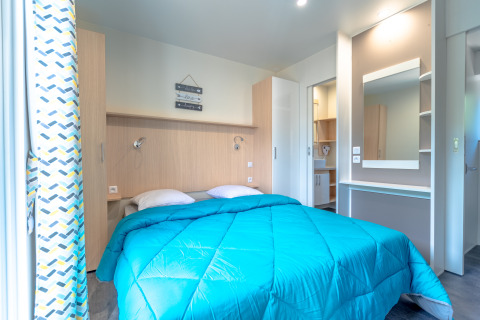 Hébergement glamping moderne au Camping Bonporteau avec lit double, armoire et grande coiffeuse.