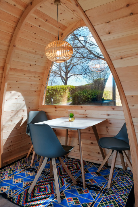Gemütliches Glamping-Familienpod mit Holzwänden, Fensterblick, blauem Teppich und Sitzbereich in Prinzenholz.