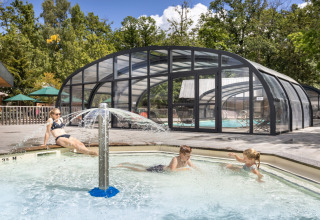 Enfants et adulte profitent de la pataugeoire et de la piscine couverte à Huttopia Versailles - Glamping Île de France.