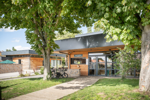 Entrance of Huttopia Versailles - Glamping Île de France with wooden exterior, trees, and parked bicycles.