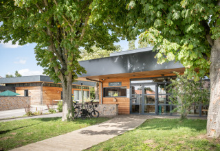 Entrance of Huttopia Versailles - Glamping Île de France with wooden exterior, trees, and parked bicycles.