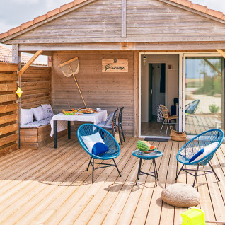 Houten buitenterras met zitplaatsen en tafel voor een glamping lodge bij Le Bellevue – Cottages en lodges Vendée.