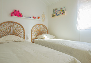 Lichte slaapkamer met twee eenpersoonsbedden in Le Bellevue – Cottages en lodges Vendée glamping.